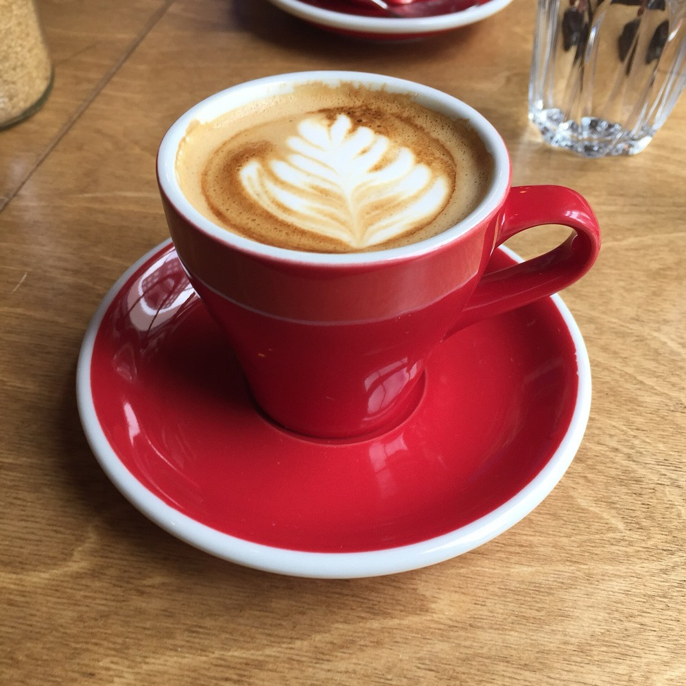 Kaffee mit Milchschaum-Muster in roter Tasse
